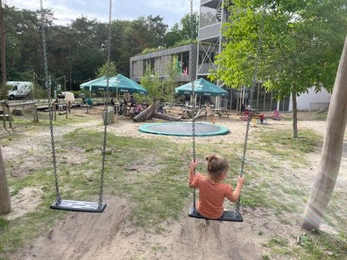 a little girl sitting on a swing in a park at Boslust in Bergen op Zoom