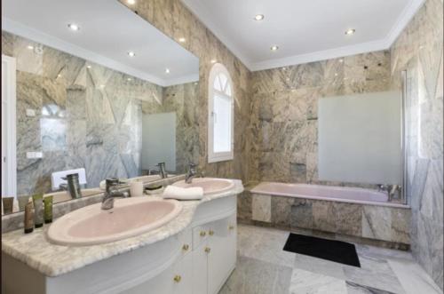 ein Badezimmer mit zwei Waschbecken und einer Badewanne in der Unterkunft Elegant Villa Retreat with Lush Gardens in Marbella