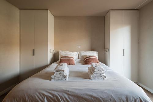 a large white bed with towels on top of it at Ruim, stijlvol gerenoveerd vakantieappartement voor 4 personen vlak bij zee en de duinen in De Panne