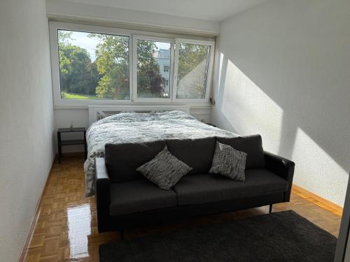 1 dormitorio con 1 cama y 1 sofá frente a una ventana en Chambre calme et confortable, accès aux pièces de vie, avec vue sur Parc, en Ginebra