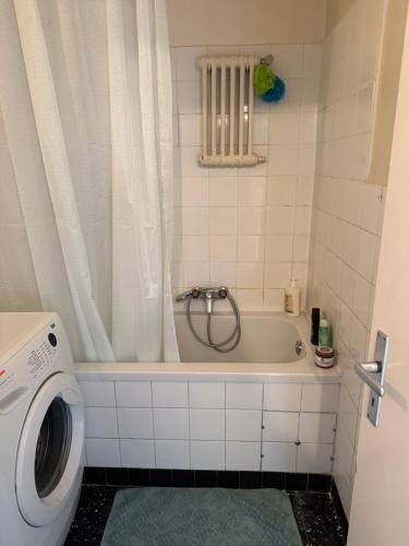 y baño con bañera y lavadora. en Chambre calme et confortable, accès aux pièces de vie, avec vue sur Parc, en Ginebra