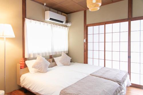 a bedroom with a bed with white sheets and a window at Ao by Perch Japan in Nagoya