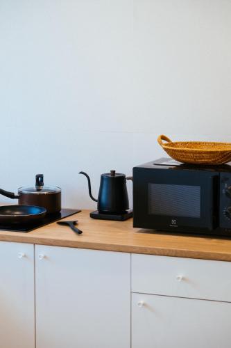 a microwave on a counter with two pots and a basket at บ้านช่วงเวลาหนึ่ง - House of Moment in Chiang Rai