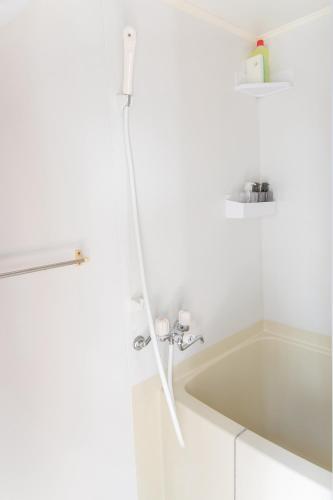 a white bathroom with a tub and a sink at Ao by Perch Japan in Nagoya