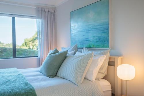Un dormitorio con una cama con almohadas y una ventana. en Lighthouse Apartment - Tūtūkākā, en Tutukaka