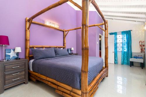 a bedroom with a wooden canopy bed and purple walls at Three Bedroom Villas in Drax Hall - Pool Gym - 24hr Security - Beach Closely in Saint Annʼs Bay