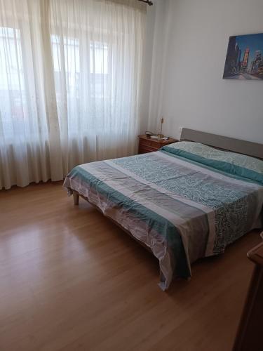 a bedroom with a bed and a window with curtains at Appartamento la Madonnina in Besenello