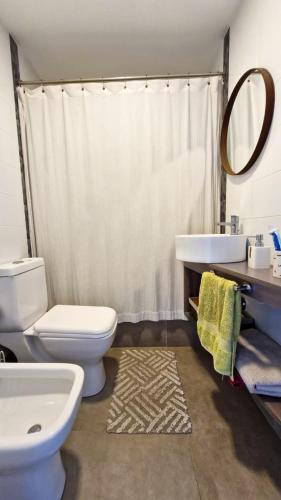 a bathroom with a toilet and a sink and a mirror at Casa Puente in Belén de Escobar