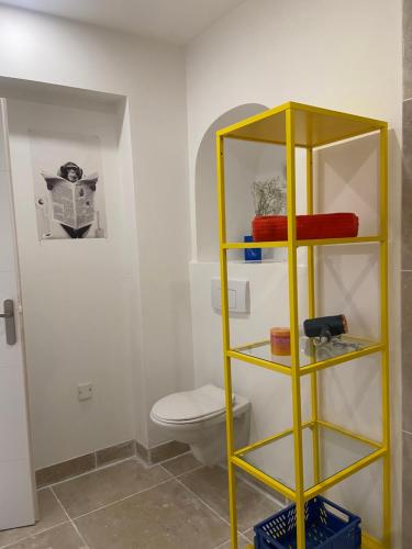 a bathroom with a yellow shelf next to a toilet at Le pop Daudet in Fontvieille
