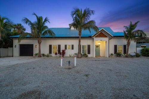 a house with palm trees in front of it at Honey I'm Holmes - New Home Near the Beach Turf in Anna Maria Island
