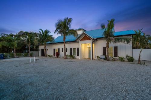 a house with a blue roof and palm trees at Honey I'm Holmes - New Home Near the Beach Turf in Anna Maria Island