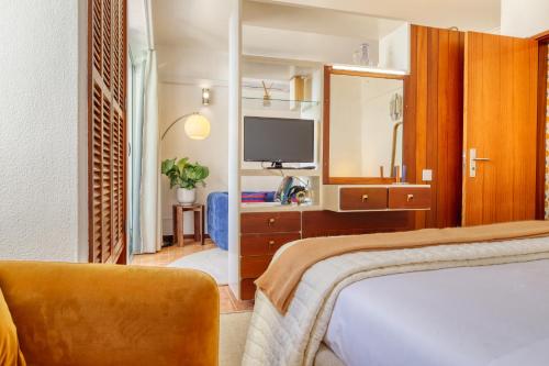 a hotel room with a bed and a television at Aida's Place, a Home in Madeira in Ilhéu do Gorgulho