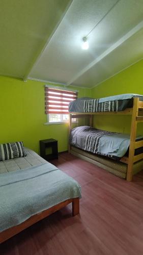 two bunk beds in a room with green walls at Cabaña donde Chapalla in Queilén