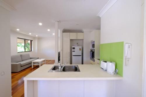 a kitchen with a sink and a living room at 2-Bedroom Apt with Terraces in Gold Coast