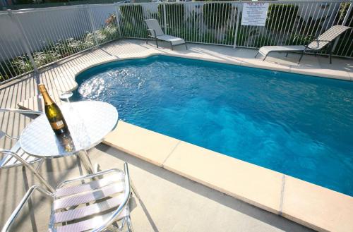 a swimming pool with a table and a bottle of wine at Pacific Coast Motel in Gold Coast