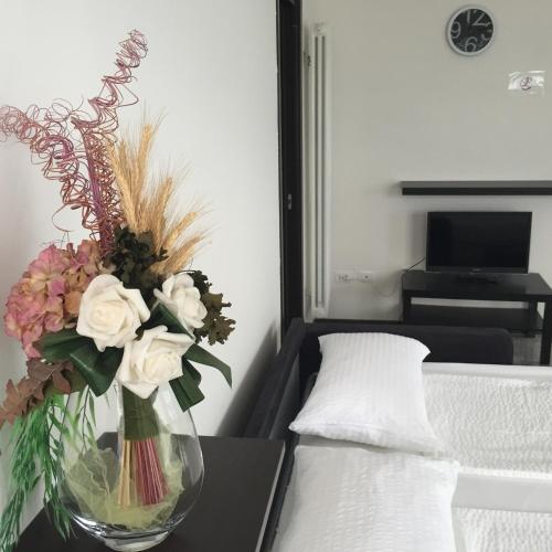 a vase of flowers on a table next to a bed at Casa Lampone in Trento