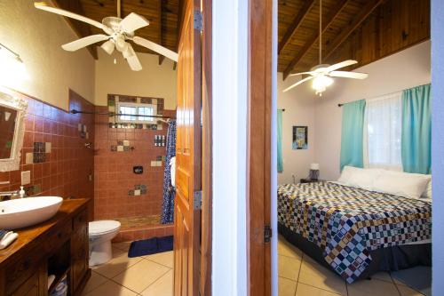 a bedroom with a bed and a bathroom with a sink at Seaside Inn Roatan in West Bay