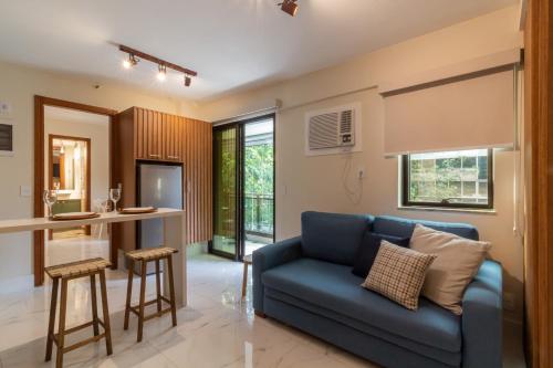 a living room with a blue couch and a kitchen at 6 minutos da Praia do Leblon - GSM103 in Rio de Janeiro