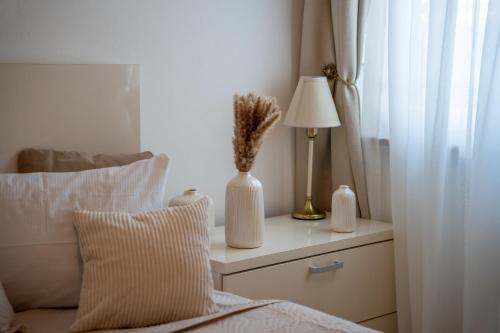Una cama con una mesa con una lámpara y un jarrón con flores en Vila Maria II, en Vinkovci