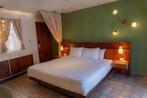 a bedroom with a large bed and a green wall at Flor de Mayo Hotel & Restaurant in Cuernavaca