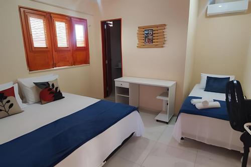 a bedroom with two beds and a desk and a window at Eficiência - Casa São Pedro - Casa Beira Mar in Camocim