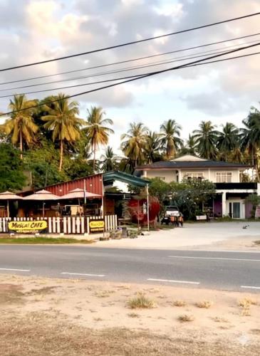 a street view of a town with palm trees at BlackSands Guests House Langkawi in Huma