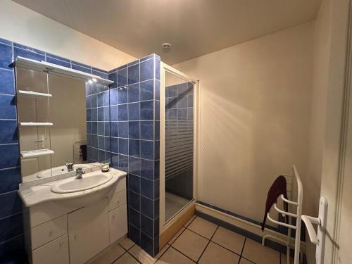 a blue tiled bathroom with a sink and a shower at Pyrenees family T3 in Aulus-les-Bains