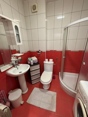 a red and white bathroom with a toilet and a sink at Apartman kod autobuske in Bijeljina