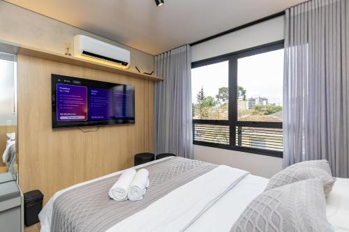 a bedroom with a bed with a tv on the wall at Studio Super Completo em Região Tranquila -EIX0202 in Curitiba