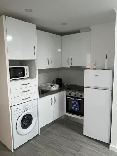 a kitchen with white cabinets and a washer and dryer at Casa do Ferrador in Moura