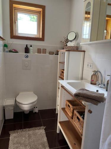 a white bathroom with a toilet and a sink at Toms Stuga Ferienwohnung in Schöneiche