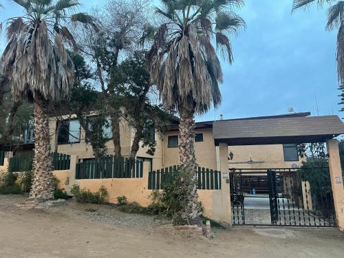 una casa con dos palmeras delante de ella en Casa de 5D para 12 personas con piscina, en Guanaquero