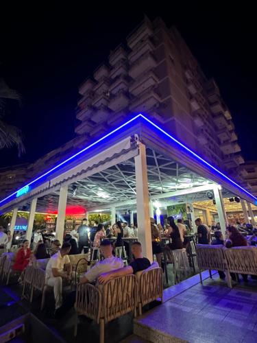 a group of people sitting at a restaurant at night at Eri Apartments 4 in Shëngjin
