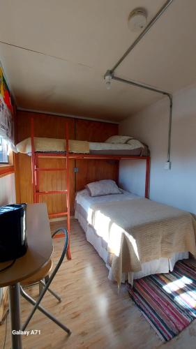 a bedroom with two bunk beds and a desk at CABAÑA EL BUHO - ESMERALDA in Puerto Natales