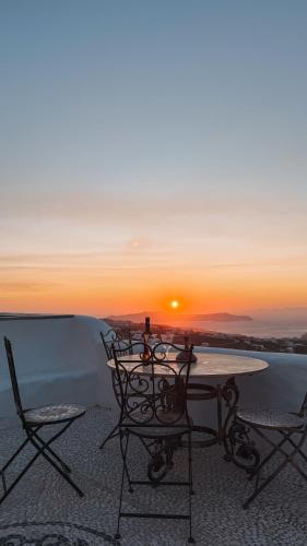 a table and chairs with the sunset in the background at Historical Villa Santa Croce in Pyrgos