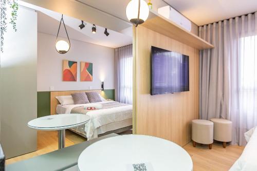 a bedroom with a bed and a table and a tv at Studio Super Completo em Região Tranquila -EIX0402 in Curitiba
