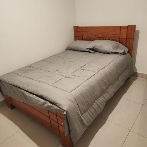 - un lit dans une chambre avec une tête de lit en bois dans l'établissement chiclayo, à La Victoria