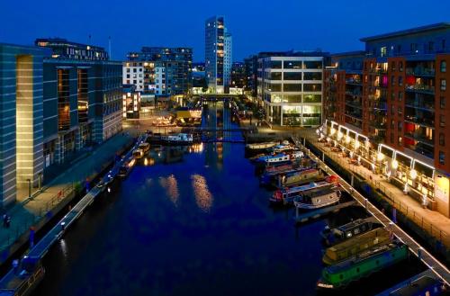 a city at night with boats in the water at Leeds Dock Apartment in Hunslet