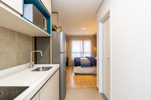 a kitchen with a sink and a living room at Studio Completo em Região Tranquila - EIX0502 in Curitiba