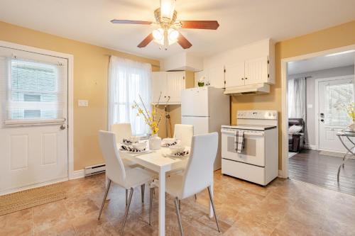 a kitchen with a white table and white appliances at Appartement moderne 3 chambres avec spa, jardin privé & parking gratuit - accès autonome in Saint-Jean-sur-Richelieu