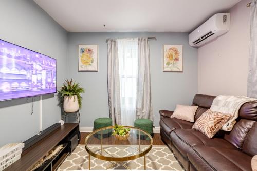 a living room with a couch and a tv at Appartement moderne 3 chambres avec spa, jardin privé & parking gratuit - accès autonome in Saint-Jean-sur-Richelieu