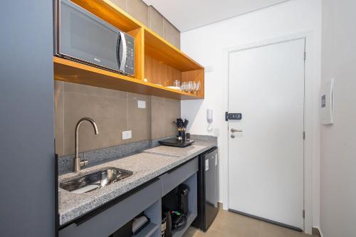eine Küche mit Spüle und Mikrowelle in der Unterkunft Studio Completo no Eixo - EIX0507 in Curitiba