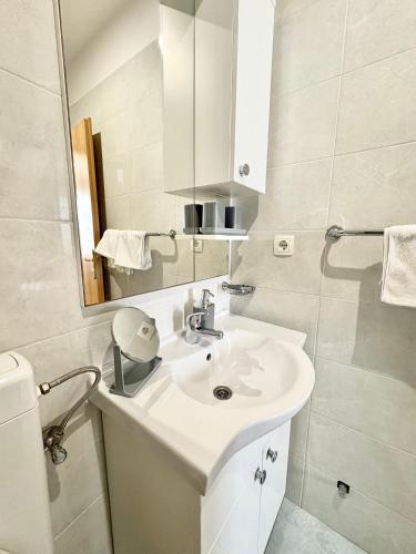 a white bathroom with a sink and a mirror at Apartment Boras Lux in Cavtat