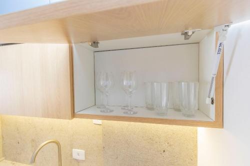 a cupboard with four empty wine glasses in it at Estúdio Completo para 5 Pessoas Com Vaga - EIX0703 in Curitiba