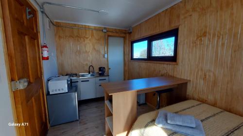 a small kitchen with a table in a tiny house at CABAÑA EL BUHO - ESMERALDA in Puerto Natales