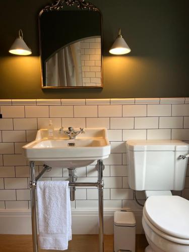 a bathroom with a sink and a toilet and a mirror at Victorian Inspired Home in Stockport