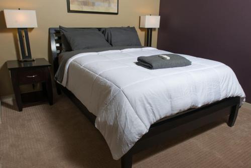 斯科茨3rd Avenue Lofts located in Old Town Scottsdale的一间卧室配有一张带白色毯子和两盏灯的床。