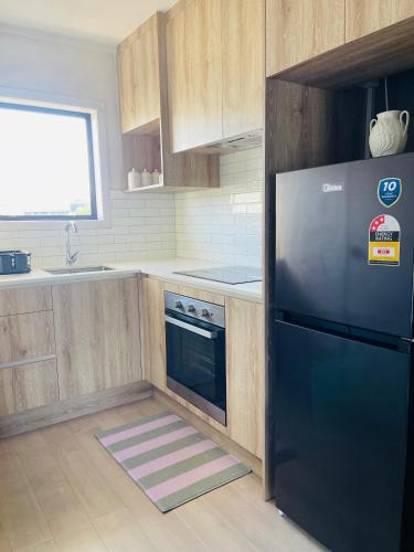 a kitchen with a black refrigerator and a sink at Sunny Tidy Corner in Ellerslie in Auckland