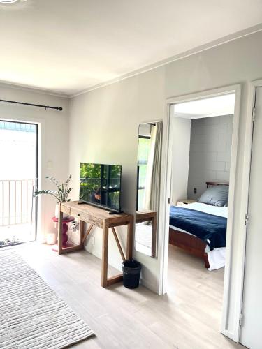 a bedroom with a bed and a desk and a mirror at Sunny Tidy Corner in Ellerslie in Auckland
