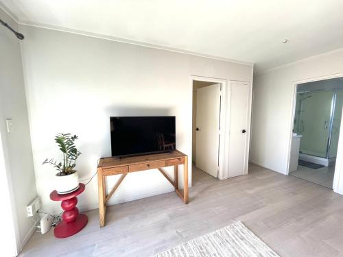a living room with a flat screen tv on a table at Sunny Tidy Corner in Ellerslie in Auckland